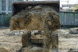 Image description: Skid loader with a Virnig bucket hauling dirt.