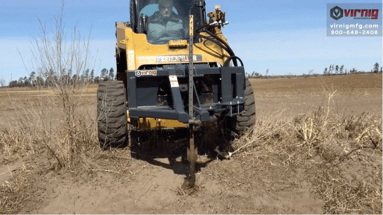 Virnig Tree Puller skid loader attachment pulling a metal post from the ground. 